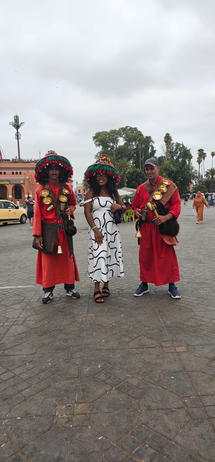 Traveller posing with traditional Moroccan water sellers in Jemaa el-Fnaa square, Marrakech