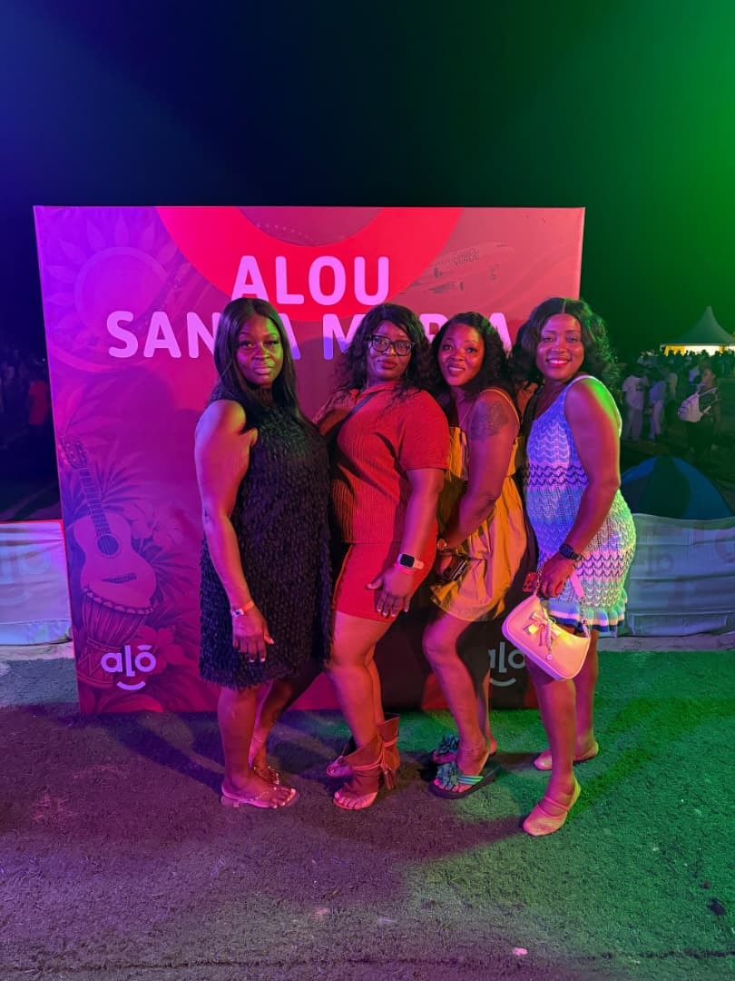 Four friends posing at the Alou Santa Marta festival backdrop at night