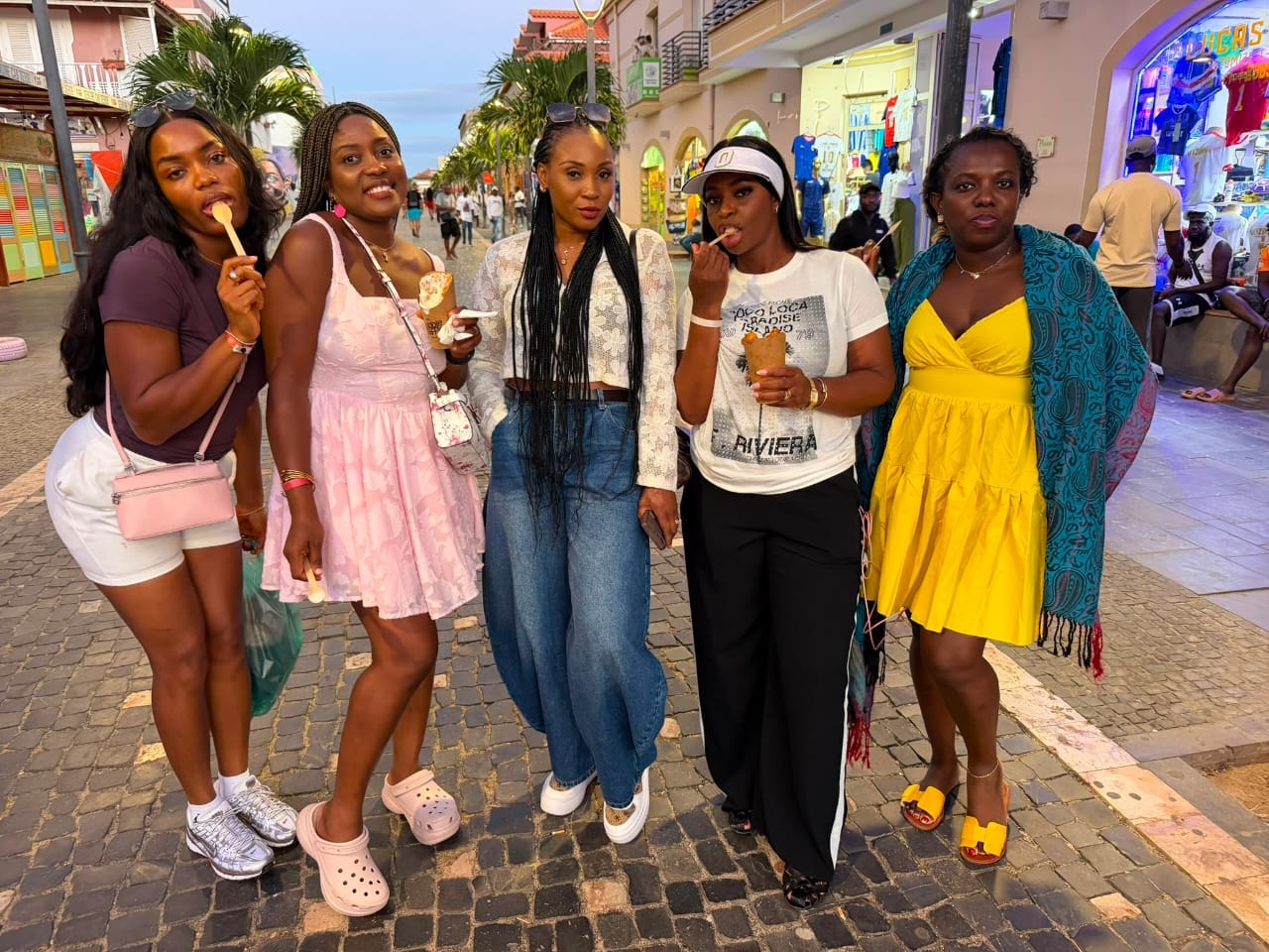 Five friends enjoying ice creams on a colourful cobblestone shopping street