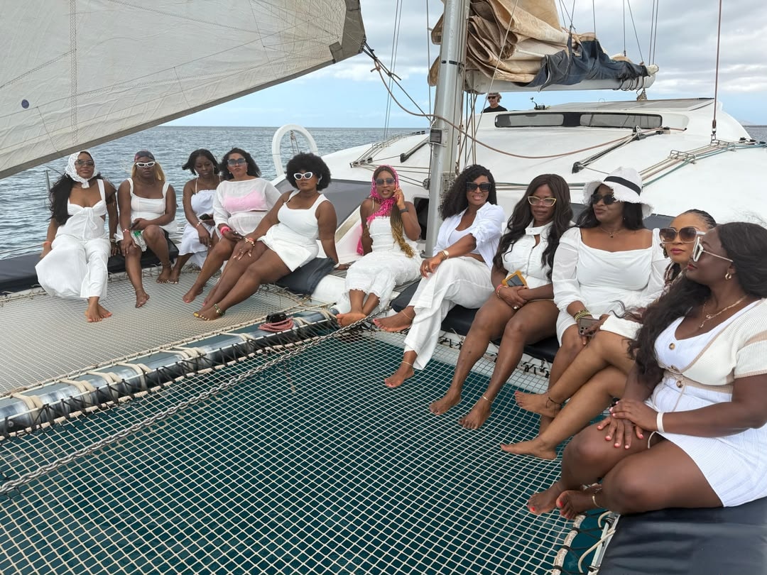 Group dressed in white aboard a catamaran sailing on the open sea