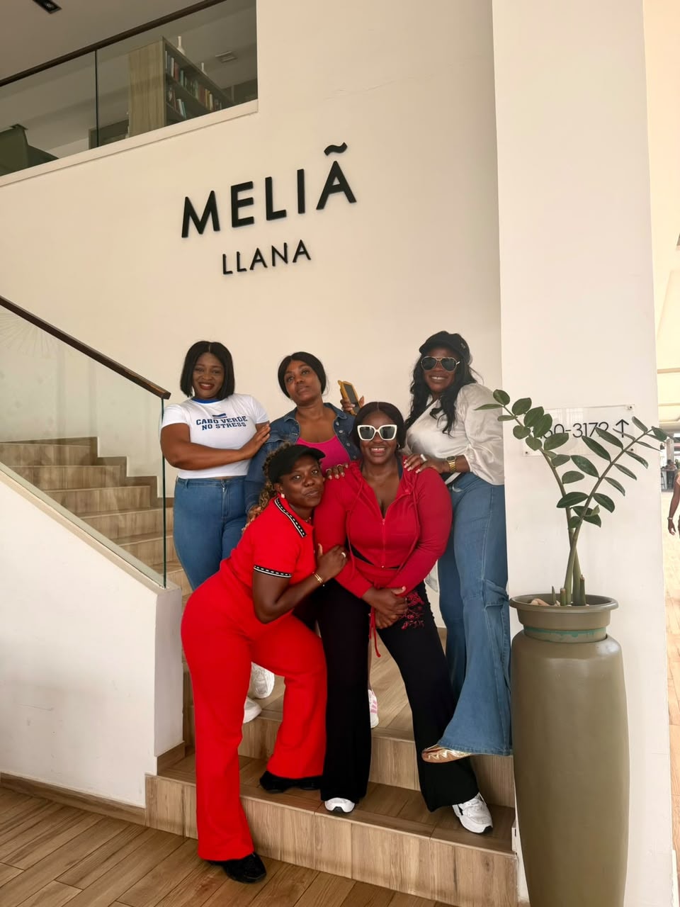 Group of five friends posing on the staircase beneath the Meliá Llana hotel sign in Cape Verde
