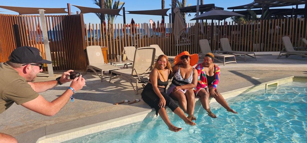 Friends laughing poolside while a photographer takes their picture at a beach resort